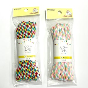 May include: Two packs of colourful shoelaces. Each pack contains 2.5 metres of shoelace, approximately 5mm wide. The shoelaces are in a red, yellow, blue, and white pattern. The other pack has pink, yellow, blue, and white shoelaces.