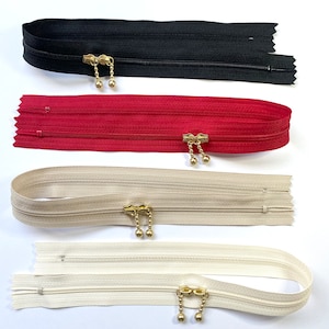 Könnte beinhalten: Vier Reißverschlüsse mit goldenen Zippern. Die Reißverschlüsse sind in Schwarz, Rot, Beige und Weiß.