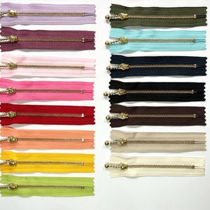 Cremalleras YKK de 10 cm, deslizador y dientes de bola color oro metalizado.