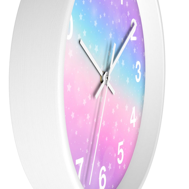 May include: White clock with a pink, purple, and blue ombre background with white stars. The clock face has white numbers and hands.
