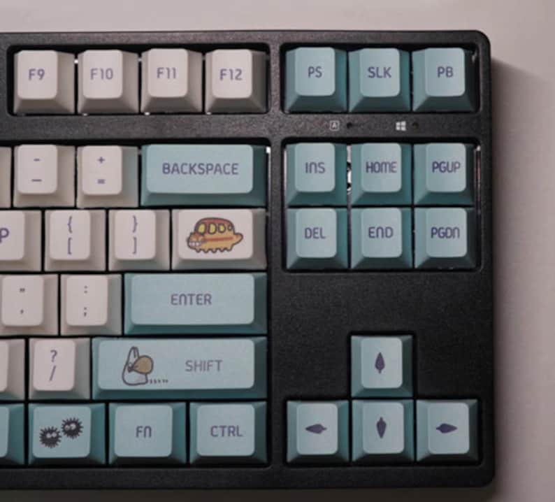 May include: A black keyboard with blue and white keys. The keys have various symbols and letters printed on them. Some keys have illustrations of a cartoon character, a rabbit, and a flower.