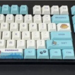 May include: A blue and white keyboard with a Totoro themed keycap set. The keyboard has a black frame and a blue and white keycap set with a Totoro design. The keycaps are made of PBT plastic and have a smooth, matte finish.