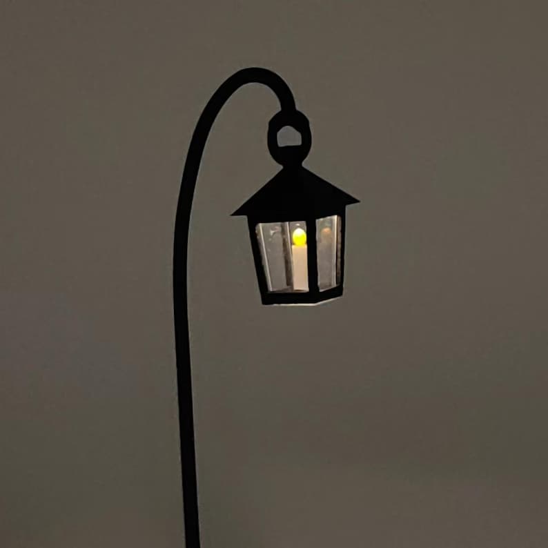 May include: A black metal lamp post with a curved arm and a black lantern with a single light bulb inside.