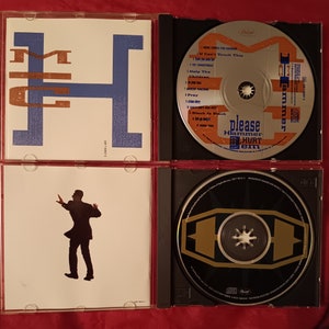 May include: A two-disc CD set with a black and gold design. The front cover features a large letter "H" in blue and orange. The back cover features a silhouette of a person in a suit. The CD case includes the text "Please Hammer Don't Hurt 'Em".
