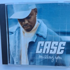 May include: CD case featuring the artist Case. The cover art has a blue and white color scheme. The artist is wearing a blue cap and coat. The text "CASE" and "missing you" are visible on the cover.