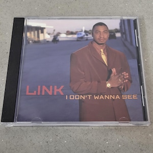 May include: A CD case with a man in a brown suit and yellow tie on the cover. The CD cover has the name "LINK" in orange letters and the text "I DON'T WANNA SEE" in white.