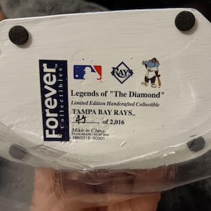 May include: White ceramic figurine of a baseball player wearing a Tampa Bay Rays uniform. The figurine is part of a limited edition collection called "Legends of "The Diamond" and is numbered 45 of 2,016. The figurine is made in China.