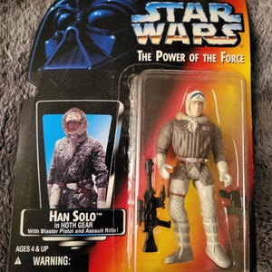 Può includere: Una action figure di Star Wars di Han Solo in equipaggiamento Hoth. La figura indossa una tuta da neve marrone e bianca con una pistola blaster e un fucile d'assalto. La confezione è rossa, gialla e nera con il logo di Star Wars e le parole "The Power of the Force".