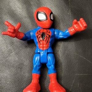May include: A Spider-Man action figure in a classic pose. The figure features a red head and boots, a blue torso and legs, and red hands. The Spider-Man logo is prominently displayed on the chest.