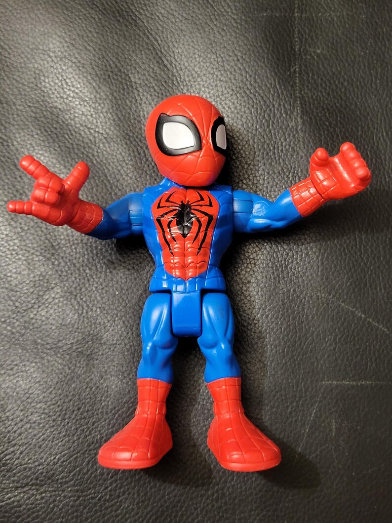 May include: A Spider-Man action figure in a classic pose. The figure features a red head and boots, a blue torso and legs, and red hands. The Spider-Man logo is prominently displayed on the chest.