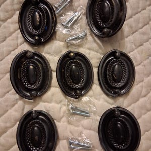 Op de afbeelding: Een witte keramische mok met een zwarte handgreep en de tekst "But First, Coffee" in een vetgedrukte, zwarte letter. De mok staat tegen een vage achtergrond, wat een gezellige setting suggereert.