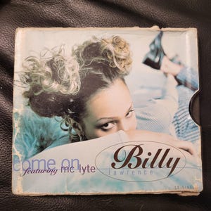 May include: A CD single case featuring a woman with curly hair, partially covering her face. The cover has the text "Come On" featuring MC Lyte and "Billy Lawrence" in a brown oval. The CD is a CD single.