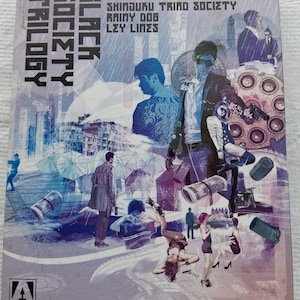 Puede incluir: Un set de Blu-ray titulado Black Society Trilogy dirigido por Takashi Miike, que incluye Shinjuku Triad Society, Rainy Dog y Ley Lines. La portada muestra un collage de personajes, paisajes urbanos y dinero en tonos azules y morados.