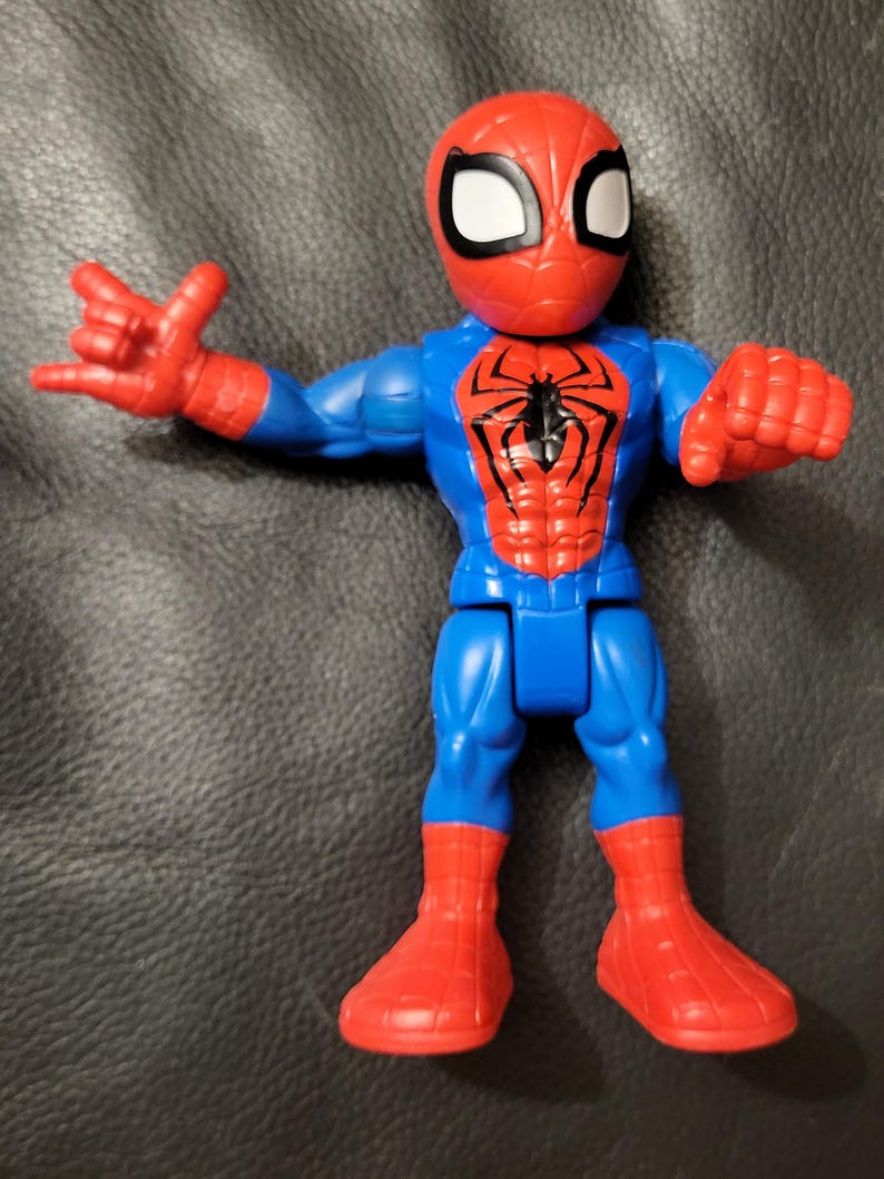 May include: A Spider-Man action figure in a dynamic pose. The figure features a red and blue color scheme, with a red mask and boots, and a blue torso and legs. The Spider-Man logo is prominently displayed on the chest.