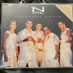 May include: A CD case featuring the boy band *NSYNC. The album cover has the band members in white outfits, with the text "TOGETHER AGAIN" and the band's logo. The case includes a sticker that says "UNRELEASED SONG & SPECIAL CD-ROM TRACK!"