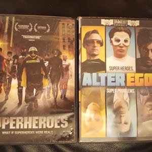 Op de afbeelding: Twee DVD-hoezen met afbeeldingen van superhelden. De eerste hoes is voor de film "Superheroes" en toont een groep mensen in superheldenpakken. De tweede hoes is voor de film "Alter Egos" en toont een groep mensen met hun gezichten bedekt door maskers of zonnebrillen.