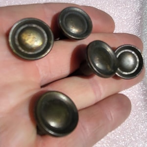 May include: A selection of antique brass drawer pulls. The pulls feature a rounded, slightly domed face with concentric rings and a dark, aged patina. These are suitable for furniture restoration or vintage projects.