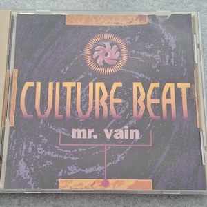 Op de afbeelding: Een vierkant CD-doosje met de albumhoes van Mr. Vain van Culture Beat. Het artwork toont een donkerpaarse wervelende achtergrond met een centraal zonachtig icoon, oranje tekst met CULTURE BEAT en mr. vain in het wit daaronder.