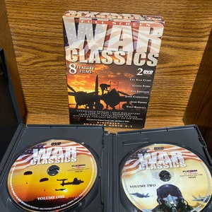 Könnte beinhalten: Ein DVD-Set mit Kriegsklassikern, das 8 Filme auf 2 Discs enthält. Das Cover zeigt ein Schwarzweißbild eines Flugzeugs vor einem rot-weiß-blauen amerikanischen Hintergrund. Die Discs sind mit "War Classics" beschriftet und zeigen Bilder von Fallschirmen und einem Piloten mit Helm.