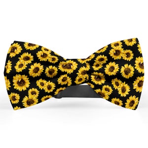 May include: A black bow tie with a sunflower pattern. The bow tie is made of fabric and has a black adjustable strap.