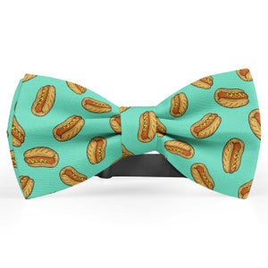 May include: A turquoise bow tie with a pattern of yellow hot dogs on it.