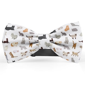 May include: White bow tie with a pattern of colorful cats. The bow tie is made of fabric and has a black adjustable strap.