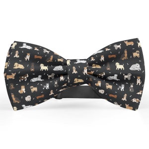 May include: A black bow tie with a pattern of various dog breeds in different colors. The bow tie is made of a soft, comfortable fabric and has a classic design.