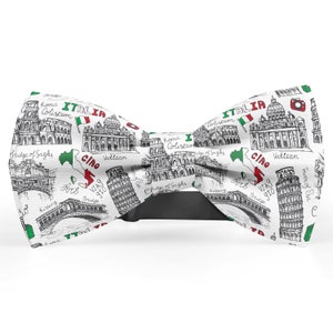 May include: White bow tie with a black bow tie strap. The bow tie has a white background with black and white illustrations of Italian landmarks, including the Colosseum, the Leaning Tower of Pisa, and the Trevi Fountain. The bow tie also features the Italian flag and the word "Italia" in red, white, and green.