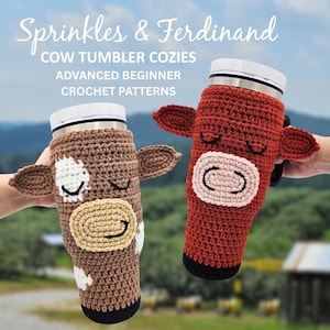 May include: Two crochet cow tumbler cozies, one brown and one red, each with a cow face design. The brown cozy has white spots and a tan muzzle, while the red one has a pink muzzle. The text "Sprinkles & Ferdinand" is at the top.