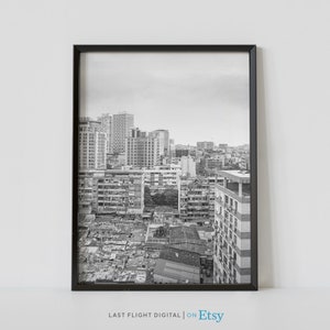 May include: A black and white photograph of a city skyline. The photo shows a dense urban area with many buildings, some of which are tall and modern. The photo is taken from a high vantage point, looking down on the city.