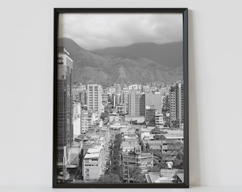 May include: A black and white photograph of a city skyline with mountains in the background. The city is densely populated with tall buildings and narrow streets. The photo is taken from a high vantage point, giving a bird's eye view of the city.