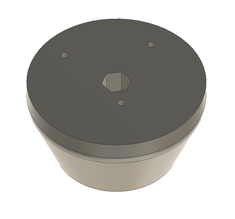 May include: A gray plastic base with a hexagonal hole in the center and two small round holes on the top. The base has a slightly rounded bottom.