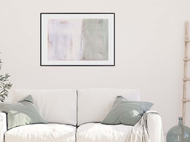 K&ouml;nnte beinhalten: Ein gerahmtes abstraktes Gem&auml;lde in Wei&szlig;- und Gr&uuml;nt&ouml;nen h&auml;ngt an einer wei&szlig;en Wand &uuml;ber einem wei&szlig;en Sofa mit gr&uuml;nen Kissen.