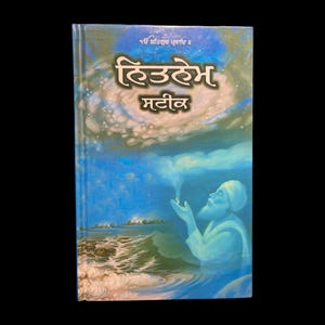 May include: A blue book with the title "हिउदेम  मतिव" in Punjabi script. The cover features a painting of a man in a blue robe with a white beard, holding his hand out towards a glowing light in the sky. The background is a blue sky with clouds and a body of water.