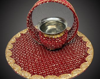 May include: A red and gold decorative tray with a round, open-top container in the center. The tray and container are covered in sequins and have a gold trim.