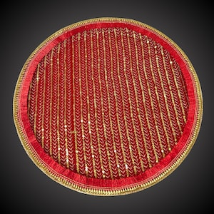 May include: A round red tray with a gold trim and a red velvet lining with gold sequins. The tray is ideal for serving food or gifts.