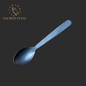 May include: A silver spoon with a rounded bowl and a long, slender handle. The spoon has a slightly textured surface.