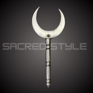 Puede incluir: Una hoja plateada en forma de media luna con un diseño floral, unida a un mango cilíndrico con bandas decorativas. El texto "SACRED STYLE" es visible en la imagen.