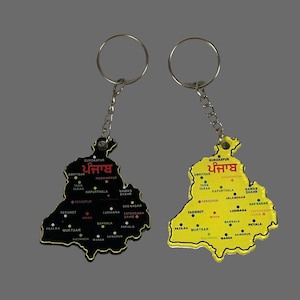 May include: Two keychains shaped like the state of Punjab, India. One is black with gold trim, the other is yellow with gold trim. Both have a silver chain and ring. The state's name is written in red, and cities are labeled.