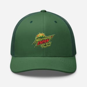 Puede incluir: Gorra de camionero verde con malla en la parte trasera y visera curva. La parte delantera presenta el logotipo "Morning Dew" en amarillo, verde y rojo. El texto "Roll Away The Dew" está debajo.