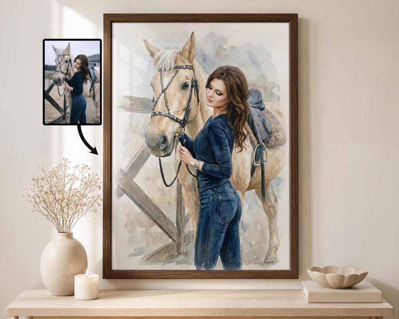 Puede incluir: Pintura a la acuarela de una mujer con cabello casta&ntilde;o largo y un caballo. La mujer lleva un top y vaqueros azul oscuro, sujetando las riendas del caballo. El caballo es de color marr&oacute;n claro con una silla de montar. La obra est&aacute; enmarcada en un marco de madera marr&oacute;n oscuro.