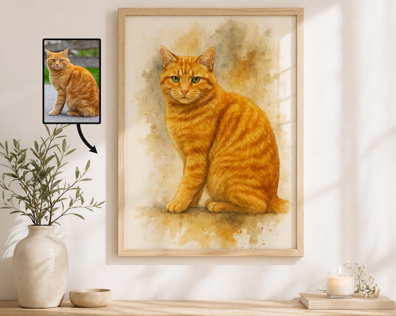May include: Watercolor painting of a ginger cat with green eyes, set in a wooden frame. The artwork features the cat in a seated position, with a soft, textured appearance. The painting is displayed on a white wall, with a small framed photo of the cat.