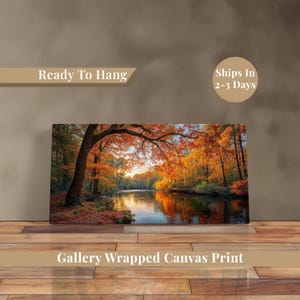 May include: Gallery wrapped canvas print of a scenic autumn landscape. The artwork depicts a river flowing through a forest with trees displaying vibrant orange and yellow foliage. The text "Ready To Hang" and "Gallery Wrapped Canvas Print" are visible.