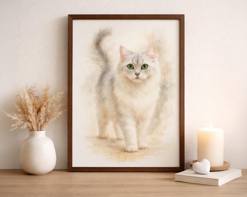 May include: Watercolor print of a fluffy white cat with gray accents and green eyes, framed in a dark brown wooden frame. The artwork is displayed on a wooden surface, with a vase of dried flowers and a lit candle nearby. The cat is the focal point.