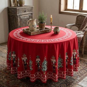 May include: A round red tablecloth featuring a repeating pattern of nutcracker figures and evergreen trees. The border includes a white geometric snowflake design. The fabric drapes over a circular table, creating a festive holiday display.