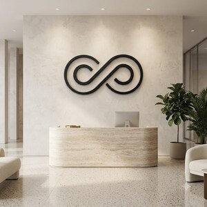 May include: A large black infinity symbol wall sign mounted on a light-coloured textured wall above a curved beige stone reception desk. The sign features a continuous line design forming a stylised loop shape centred in the space.