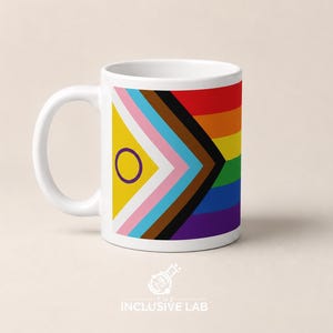 Puede incluir: Taza de cerámica blanca con un diseño de la bandera del Orgullo Progresista y el texto "INCLUSIVE LAB". La taza tiene un asa curva y una forma cilíndrica. El diseño incluye rayas de arcoíris y formas geométricas.