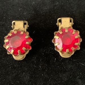 May include: A pair of vintage clip-on earrings with red glass stones set in gold-tone metal.