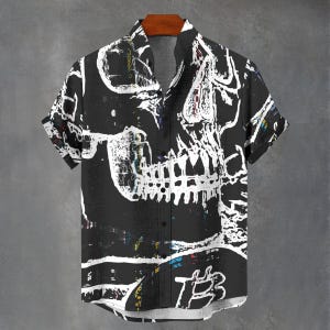 Könnte beinhalten: Schwarzes kurzärmeliges Hemd mit einem großen weißen Totenkopf-Motiv. Das Hemd hat eine Knopfleiste und einen Camp-Kragen. Das Totenkopf-Design ist mit verschiedenen Farben und Texturen detailliert, was einen kühnen und künstlerischen Look erzeugt.