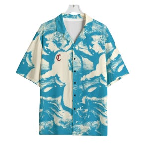 May include: Short-sleeved shirt with a distinctive pattern in blue and cream. The design features abstract figures. A small, red letter "C" is on the left chest. The shirt has a classic collar and a relaxed fit.